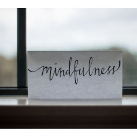 Image: White reminder card with hand written note which reads "mindfulness" on a window ledge.