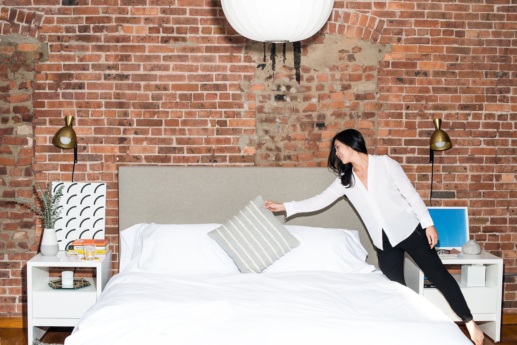 Tze Chun, crisp white sheet devotee, finishes off her bed with a decorative pillow. 