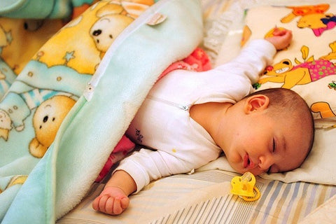Sleeping baby in baby sleepsuit during swaddle transition