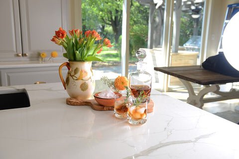 cocktail on countertop with ceramic pitcher full of flowers