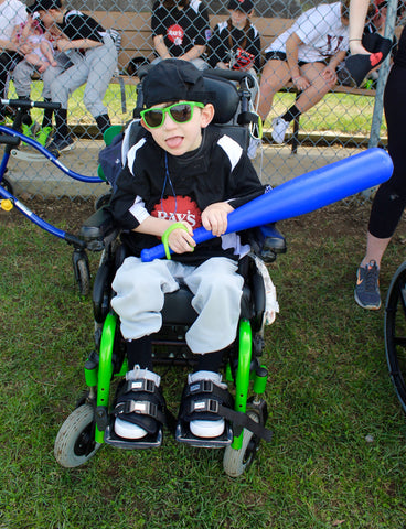 special needs child in a wheelchair holding a baseball bat with eazyhold universal cuff