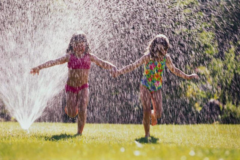 children playing in a sprinkler