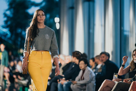 Girl with yellow pants and grey crewneck walks down runway