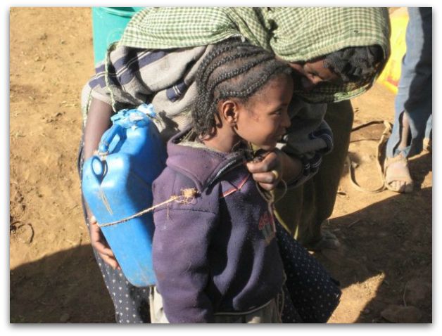 Small Ethiopian girl carrying water with a jerry can