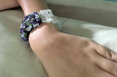 Stretchy bracelet of clear, purple, and green glass beads