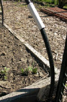 A close-up of the support hoops made of flexible irrigation tubing that are used to create bird netting structures over a garden bed - Renee's Garden
