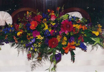 A dazzling flower arrangement including zinnias, irises, lilies, and ferns