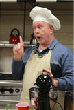 Jim Long standing up with white chefs hat on and an apron.