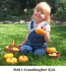 Beth's 4 year old granddaughter, Kyla, holds a mini pumpkin, surrounded by several more, while playing on a lawn - Renee's Garden
