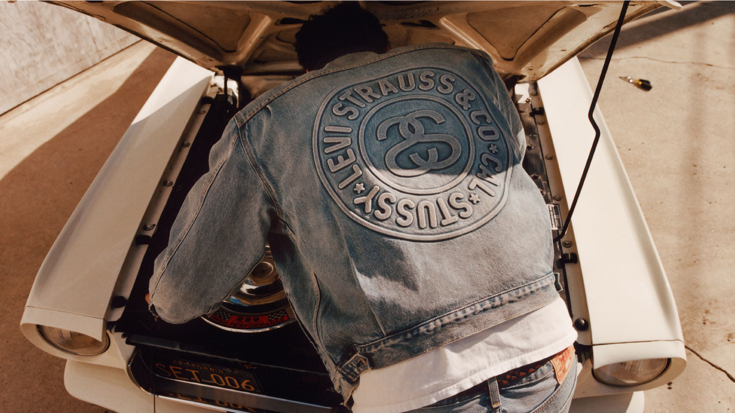 身穿 Stussy x Levi's 牛仔樓的男士正在修理他的汽車 - Levi's 香港