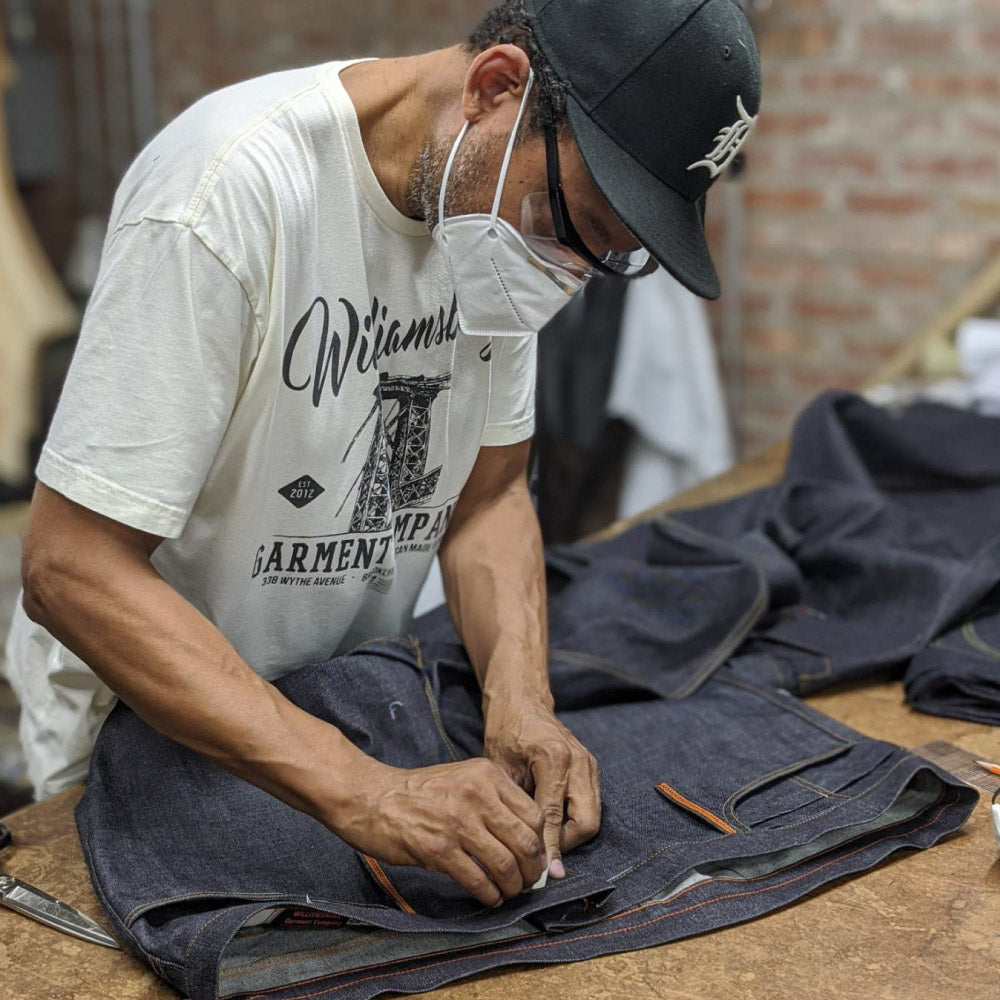 Denim designer Maurice Malone working on custom made jeans in mask during COVID-19