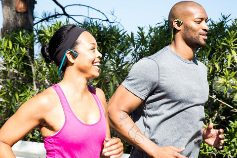 A man and woman out jogging wearing bone conduction headphones