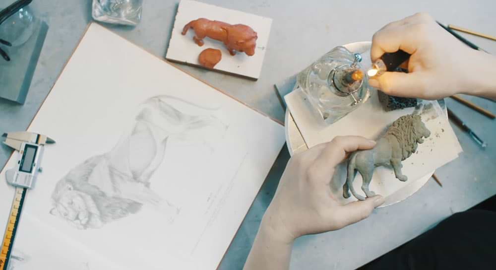 Artist drawing of a lion during the Schleich creation process. Tools are shown to ensure scale accuracy.