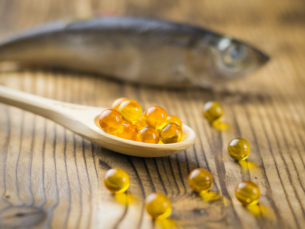 Krill oil vs. fish oil: A fish behind a spoonful of fish oil gel capsules