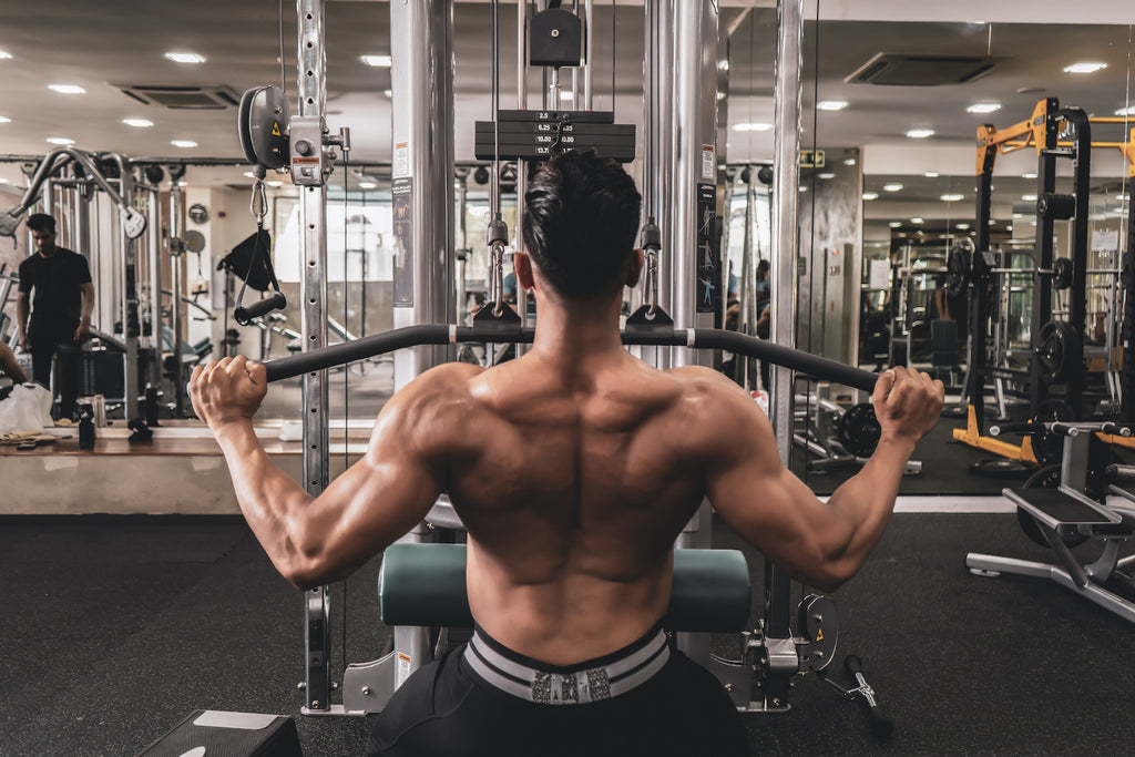 A man doing upper back exercises on the weight training equipment at the gym