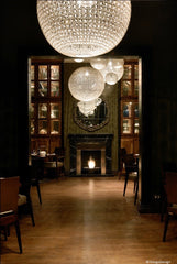Restaurant with tables on one side and bar on the other. Large ball shaped chandeliers give a 1930's effect