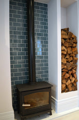 Wood burner in family kitchen against brightly tiled wall