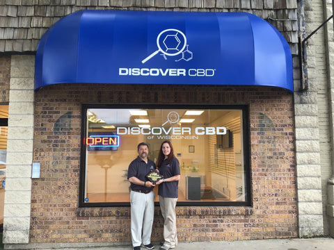 man and woman outside of store front holding plaque