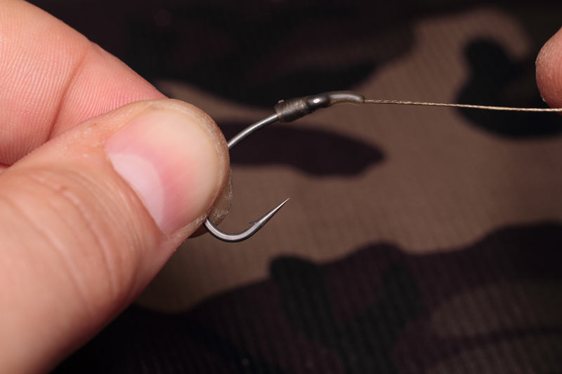 Slide the line aligner down the hooklink and over the eye of the hook until it covers the knotless knot