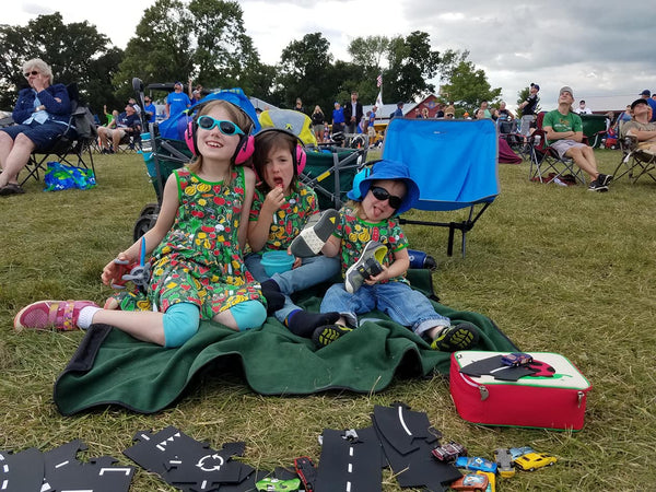 3 kids sitting at airshow at oshkosh