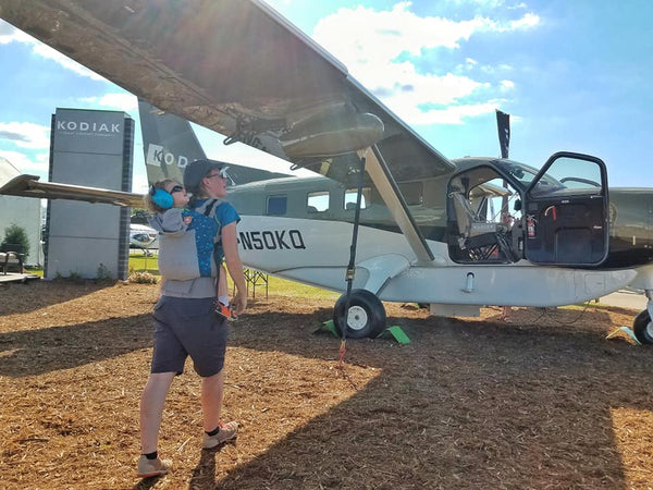 mom with toddler in Tula carrier under Kodiak aircraft wing