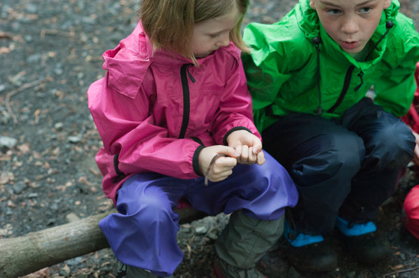 boy and girl sitting on log in raingear for Biddle and Bop