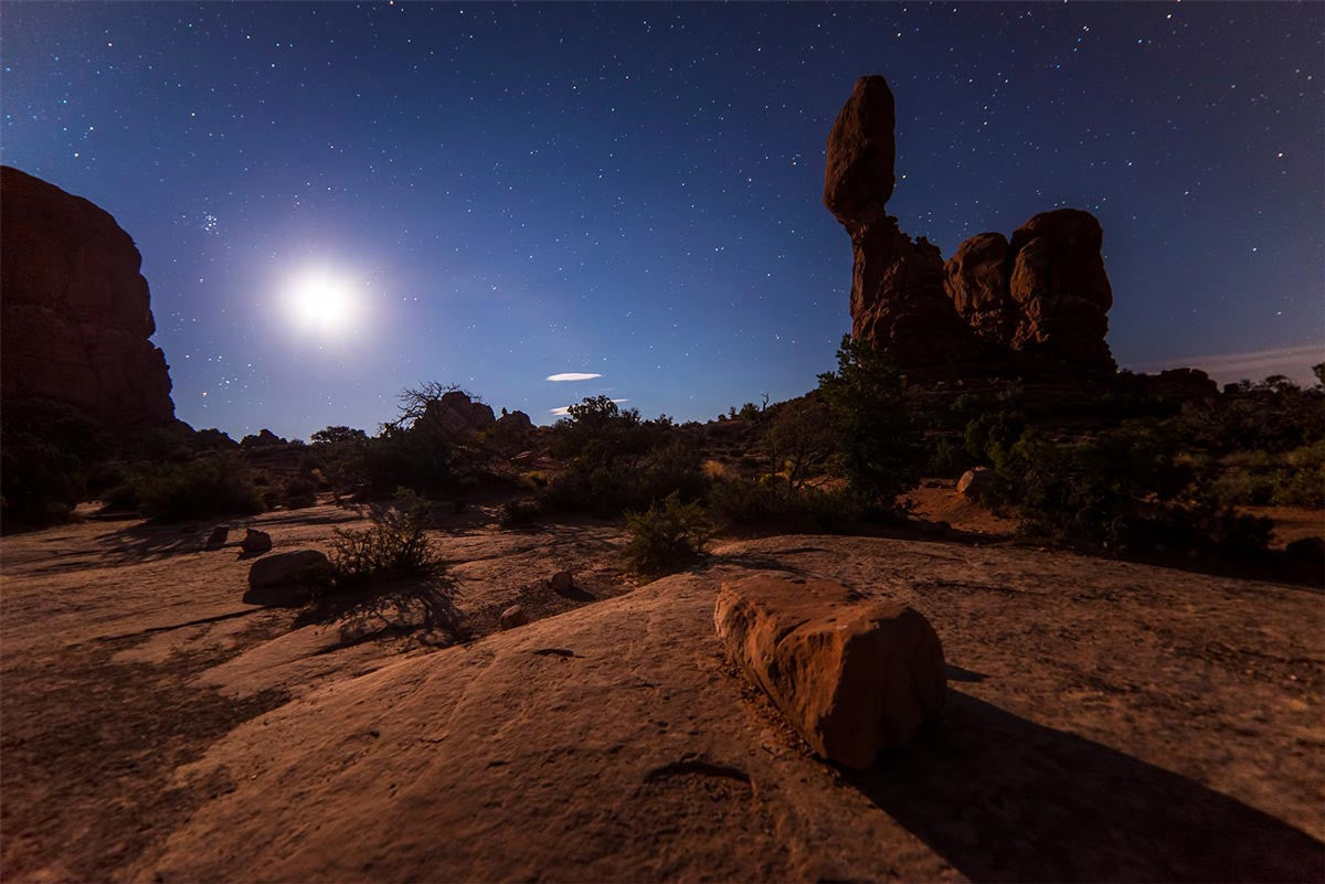 Starry sky over a rocky desert landscape.