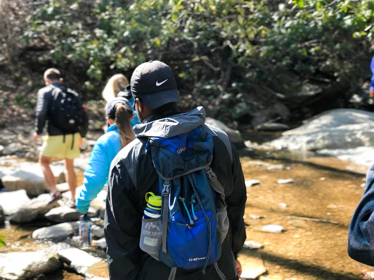 Group of hikers crossing a small stream as they hike.