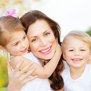 Single mom with her two happy children, smiling and playing outside on a nice day.