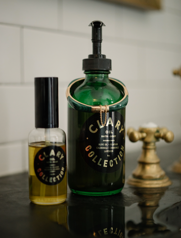 Regular and Travel Size Clary Bath and Body Oil on Bathroom Sink