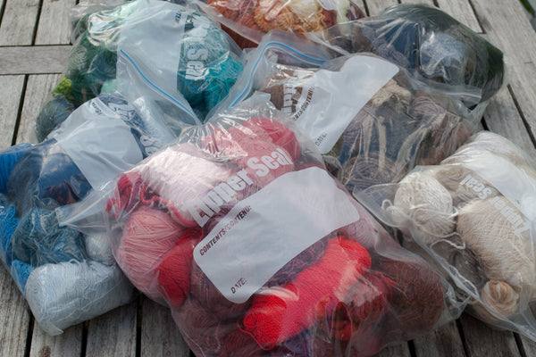 Large ziploc bags full of yarn scraps, sorted into colours