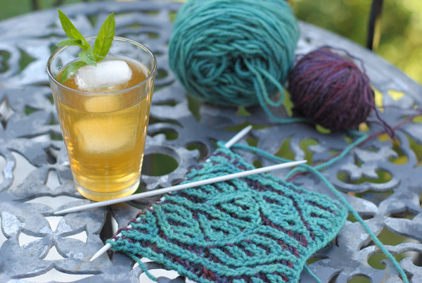 Glass of iced tea next to knitting