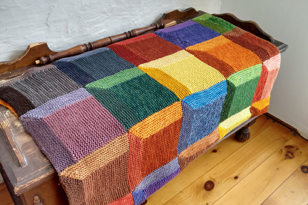 colourful knit attic windows blanket folded neatly and lying across a cedar chest