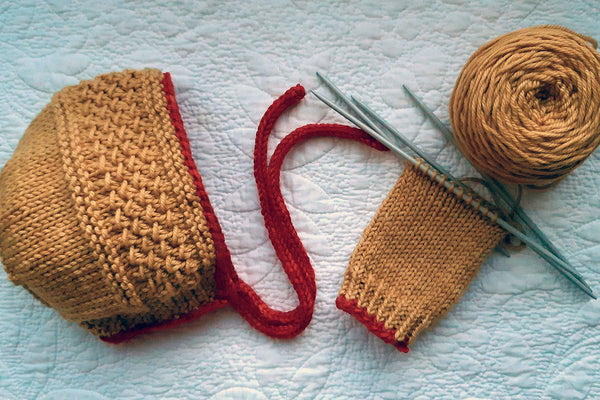 Handknit baby bonnet and legwarmers with pomegranate-dyed yarn