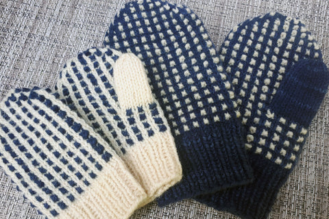 Two pairs of mittens, adult pair is dark blue with natural contrast, child's pair has colours reversed