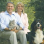 Man and Woman sitting on bench with dog and cat