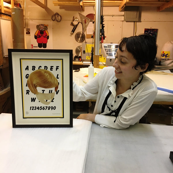 Yvette holding a finished Eva Lake portrait custom framed and floated at Frames and Stretchers in the Lower East Side.