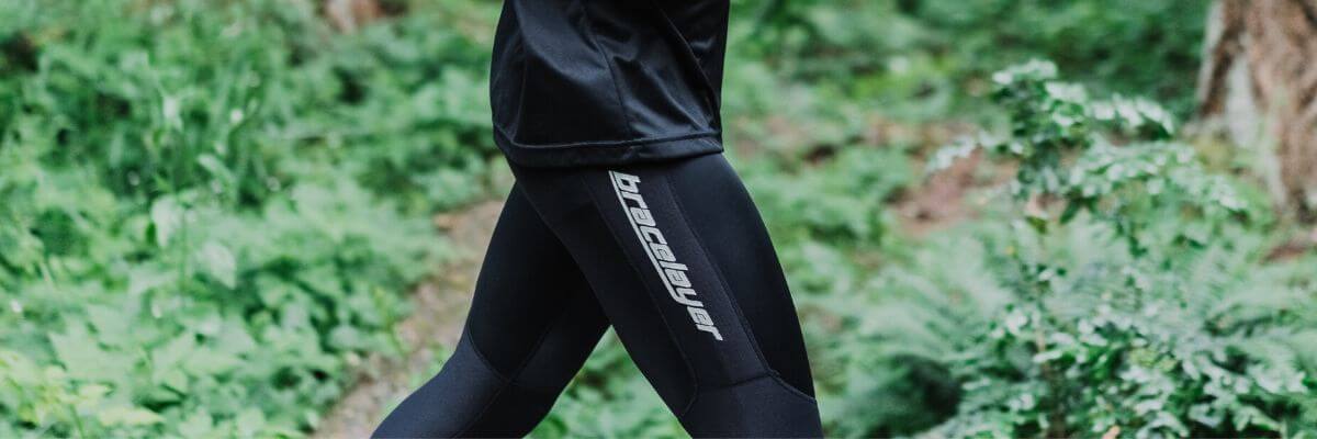 A close up image of the hips and knees of a runner. They are wearing Bracelayer's compression pants for knee support running.
