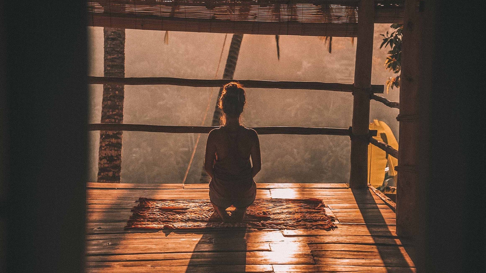 girl meditating on a deck during sunrise