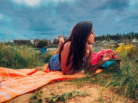 Girl at the beach sitting on a hammam towel