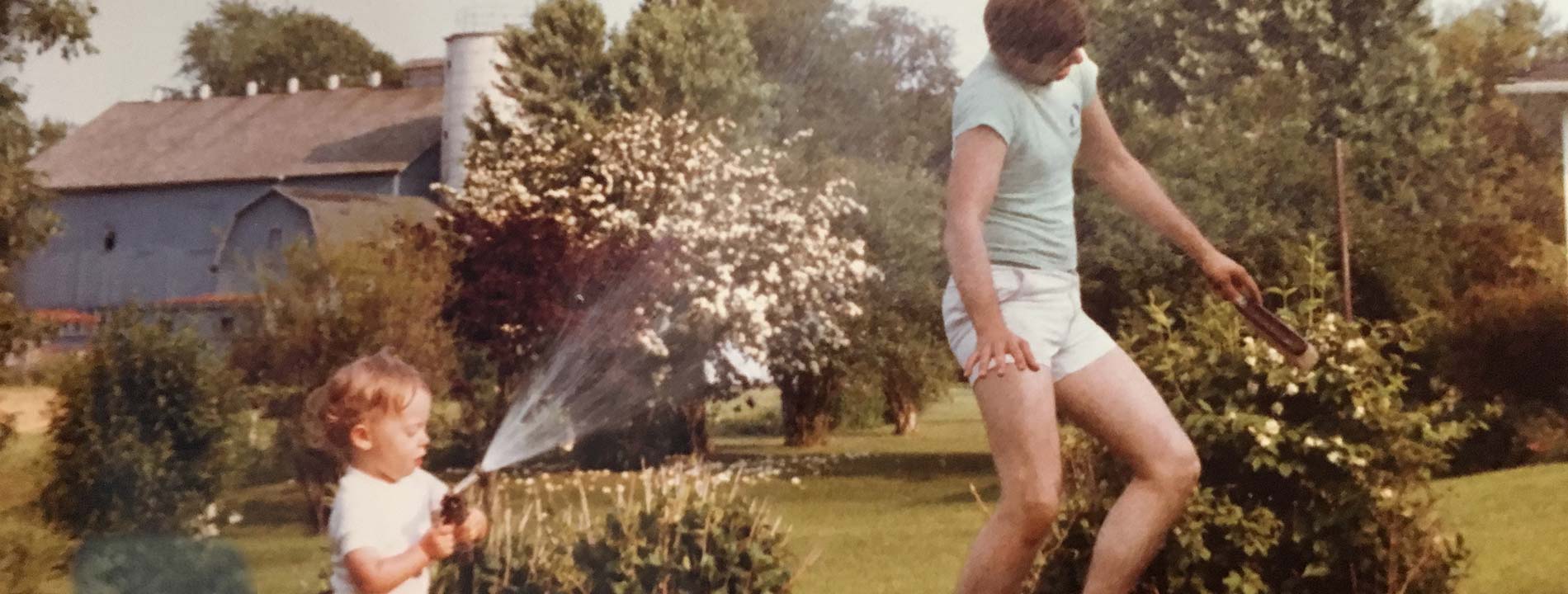 Young Ryan Martin spraying his dad with a water hose