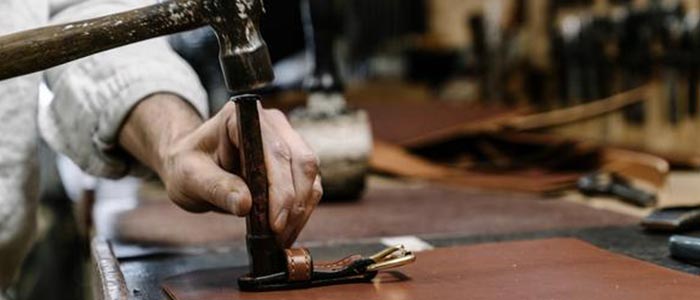 Craftsman securing a buckle on a leather bag