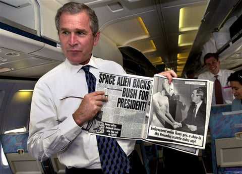 George W. Bush holds an issue of the Weekly World News that claims that a space alien endorses Bush for President.
