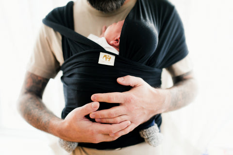 father dad holding his newborn baby in a Mezaya stretchy baby wrap black. 