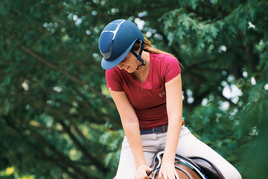 Equestrian in a wide brim helmet riding horses outside