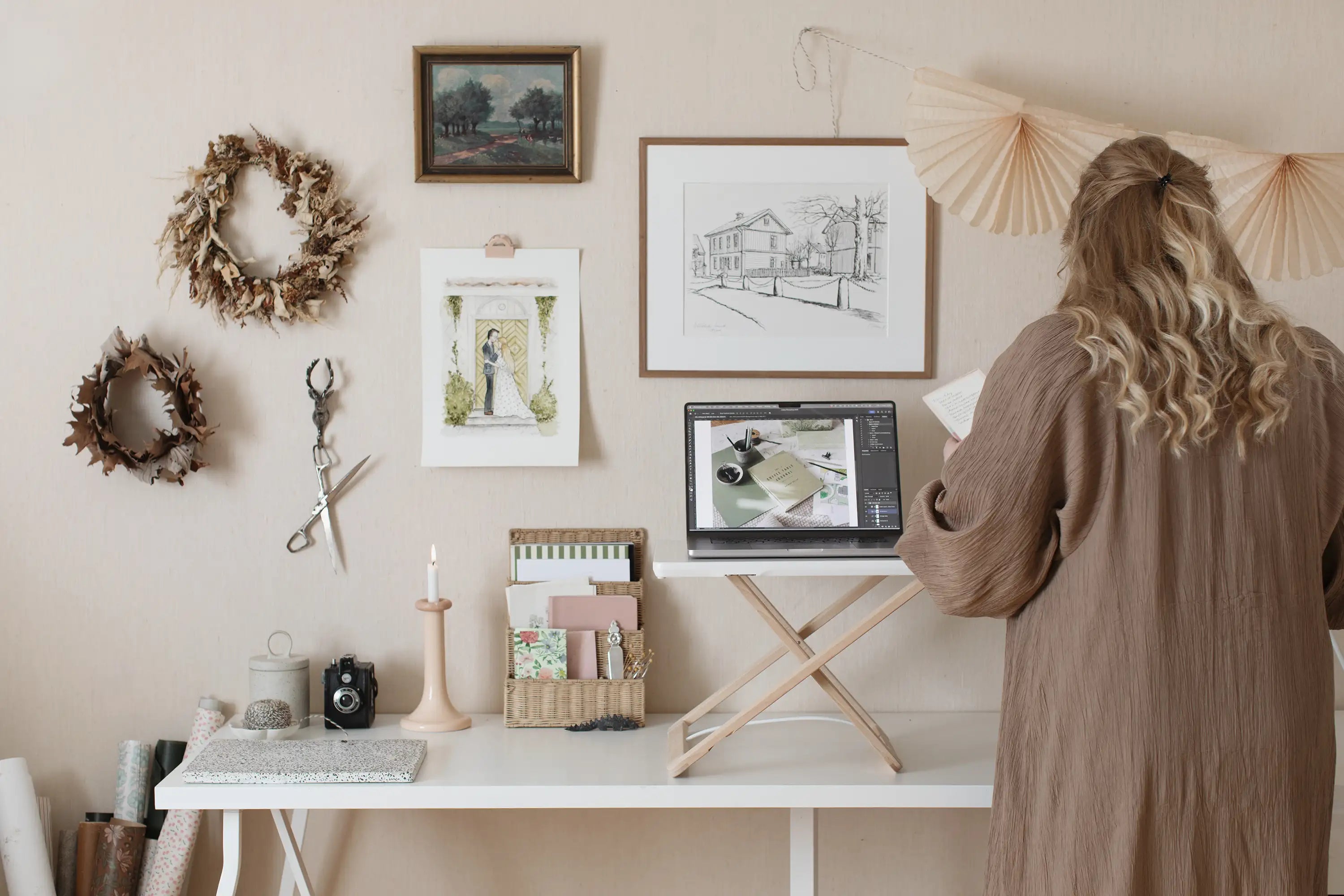Woman working standing up using Freedesk Desk Riser Original Compact in a home studio with craft materials