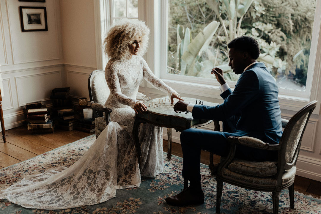Bride and Groom seated playing chess Bride in Beverly Lace Wedding Dress by Claire Pettibone