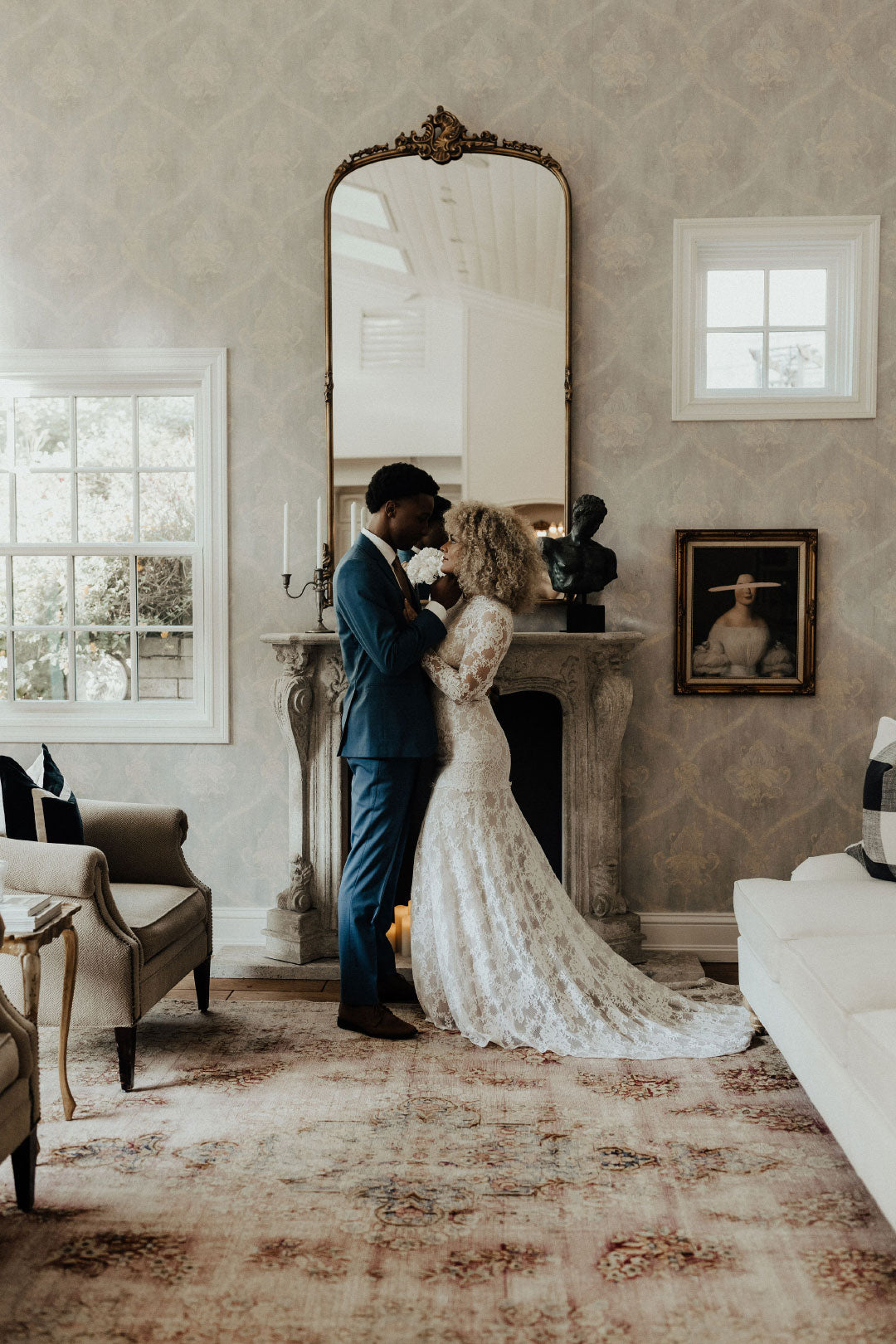 Bride and Groom embrace by fireplace Bride in Lace Wedding Dress by Claire Pettibone