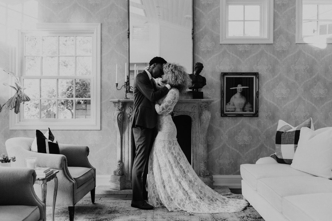 Black and white photo of bride and groom kissing by fire place