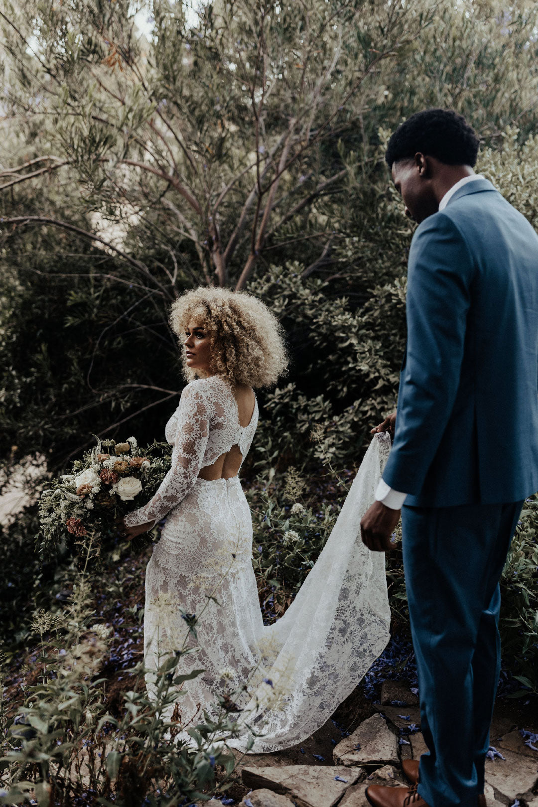 Bride in Beverly lace wedding dress by Claire Pettibone Groom hold lace train